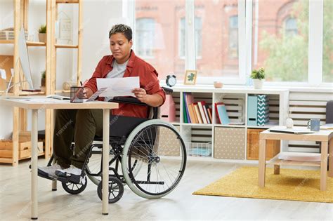 Mujer con discapacidad trabajando en un ordenador mientras su hijo estudia cerca, mostrando equilibrio y superación
