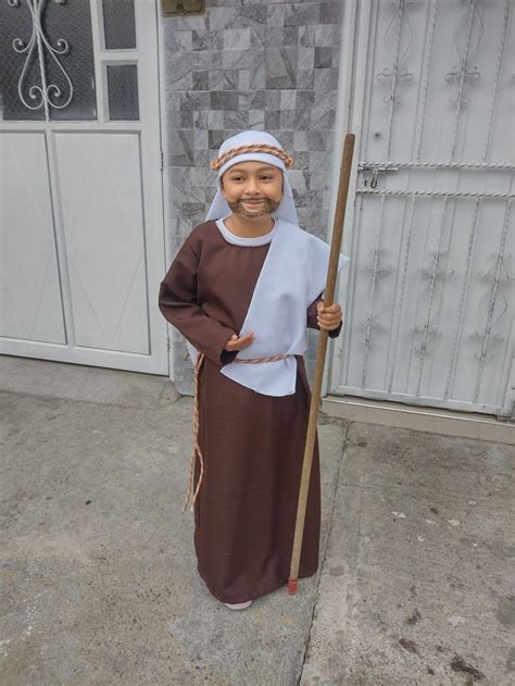 Hombre adulto vestido con disfraz de pastor tradicional, con ovejas en un entorno rural