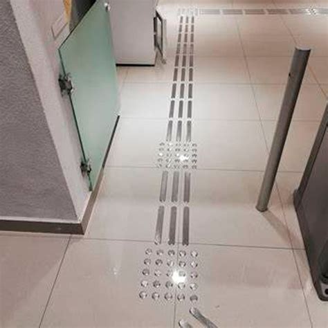 Instalación de franjas podotáctiles de acero inoxidable en un espacio público.