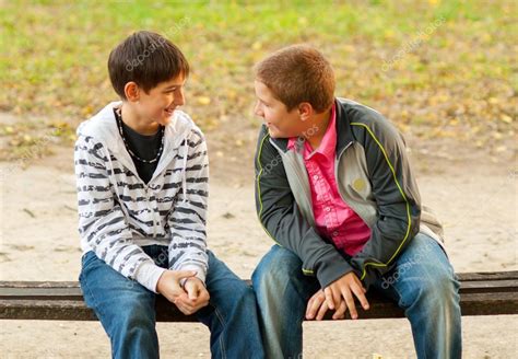 Dos hombres conversando en una plaza, uno joven y otro anciano.