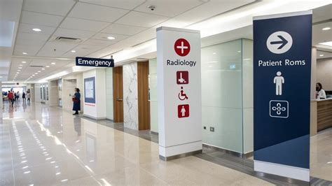Señalética universal en un pasillo de hospital, incluyendo braille y pictogramas