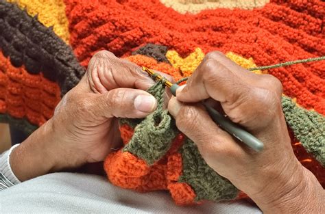 Foto: Berta Rodríguez tejiendo en su casa, rodeada de sus productos de lana hechos a mano.
