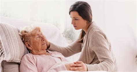 Foto de una persona cuidando a un familiar enfermo, mostrando signos de agotamiento.