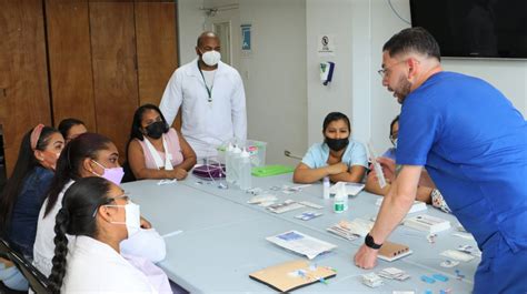 Fotografía de una sesión de capacitación para cuidadores en un CESFAM, con participantes atentos y un profesional de la salud explicando.