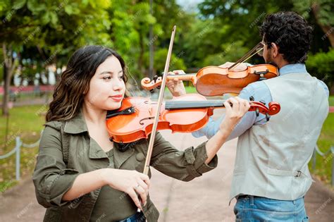 Foto de dos violinistas tocando con alegría y complicidad en un escenario
