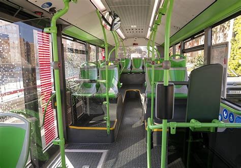 Interior de un autobús con espacio para sillas de ruedas y asideros