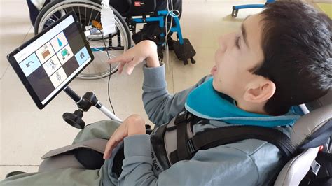 Profesional de apoyo mostrando cómo usar una tableta adaptada a un niño