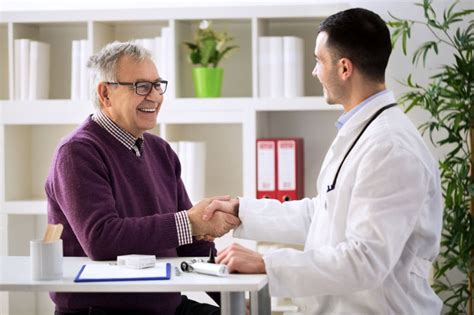 Foto de un médico interactuando amistosamente con un paciente mayor durante una consulta