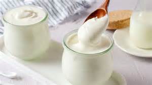 Persona mayor sonriendo mientras consume un producto lácteo, como un vaso de leche o un yogur