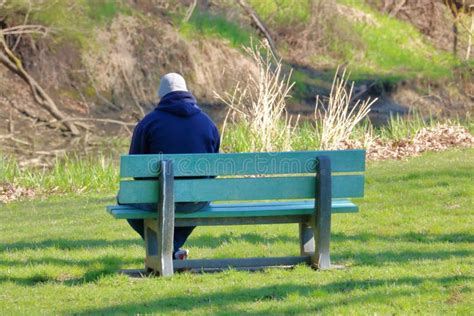 fotografía de una persona mayor sentada sola en un banco del parque