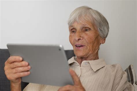 Fotografía de un adulto mayor usando una tablet sonriendo