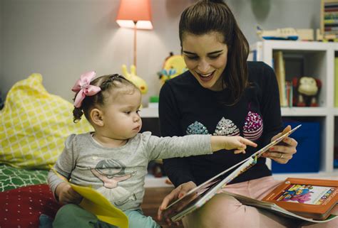 Bebé o niño pequeño interactuando con un adulto, señalando objetos y balbuceando.