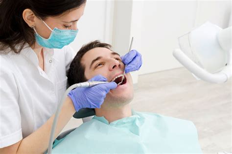 dentista atendiendo a un paciente adulto mayor en una clínica dental, enfoque en la comodidad y la historia clínica