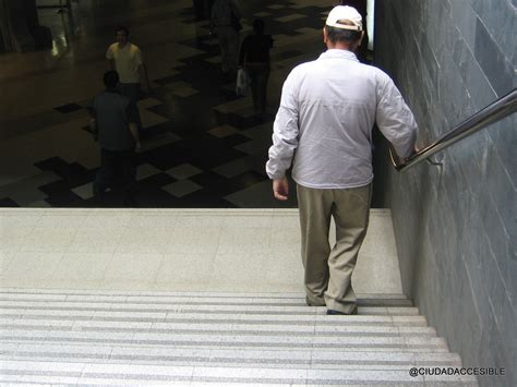 Persona mayor utilizando pasamanos en una escalera segura