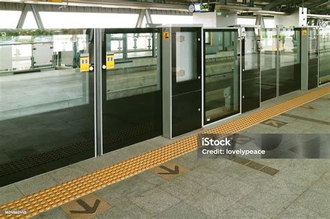 Fotografía de una franja táctil guía en el andén de una estación de Metro, señalizando el camino hacia un ascensor.