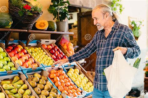 Anciano vendedor de fruta en Civita, Italia, con cajones de nísperos y una balanza
