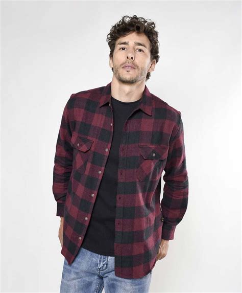 Hombre mayor vistiendo una camisa escocesa café, sonriendo