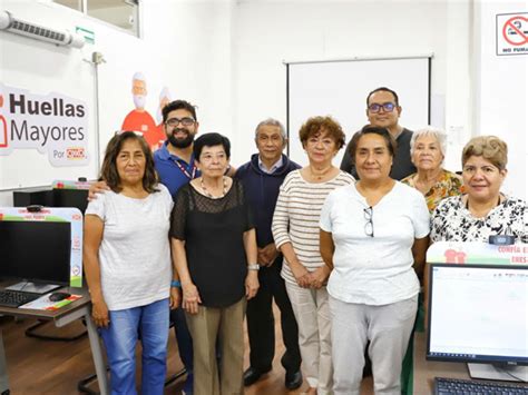 Fotografía de un taller de computación donde adultos mayores interactúan con dispositivos digitales