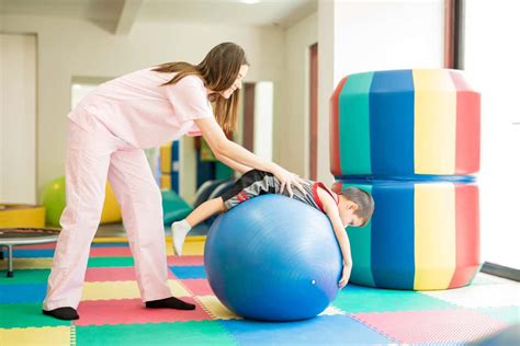 Foto de niños realizando actividades psicomotoras o ejercicios de fisioterapia con un terapeuta.