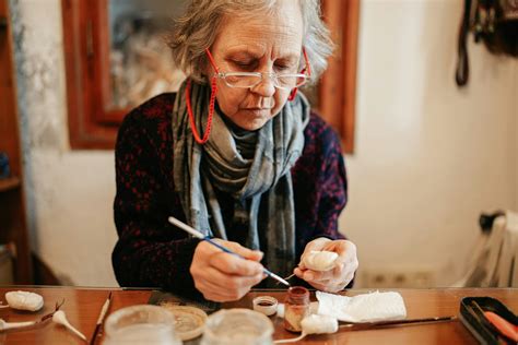 Imagen de un adulto mayor concentrado haciendo una manualidad, como tejer o pintar