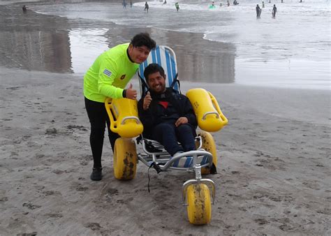 Ilustración de una silla anfibia (anfibuggy) en la playa, asistida por socorristas