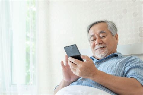 Foto de una persona mayor sonriendo mientras usa un teléfono con botones grandes