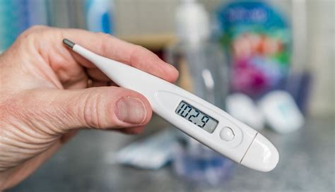 Fotografía de un termómetro digital midiendo la temperatura en la frente de un adulto mayor