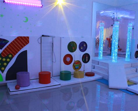 Diseño interior de un espacio de estimulación sensorial móvil para niños, con luces suaves, texturas variadas y dispositivos para la coordinación.