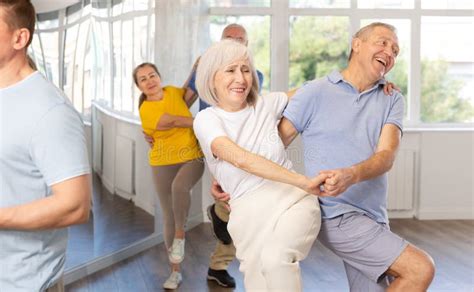 Foto de una clase de baile grupal animada con personas mayores interactuando y riendo