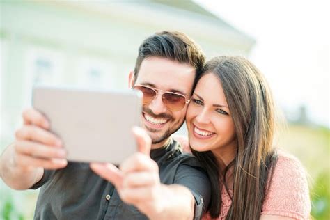 Foto de una pareja feliz con discapacidad visual, usando una aplicación en un teléfono para leer un test de embarazo con ayuda de un voluntario en videollamada