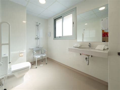 Foto de un baño adaptado para adultos mayores con silla de ducha y barras de apoyo