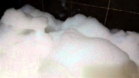 Piscina llena de espuma con una persona intentando limpiarla