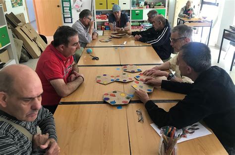 Foto de personas mayores participando activamente en un taller de estimulación cognitiva, riendo y colaborando.