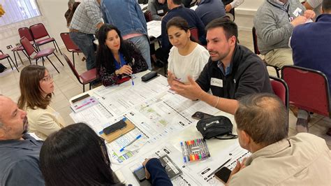 Grupo de personas participando activamente en un taller, con gráficos y materiales informativos.