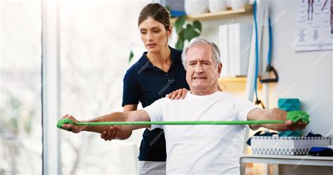 Fotografía de un paciente anciano realizando ejercicios de rehabilitación de cadera con un fisioterapeuta.
