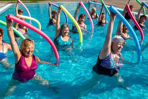 Personas mayores usando churros de piscina durante una clase de aquagym