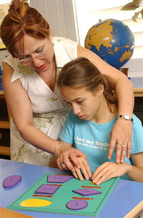 Maestra explicando una actividad a un niño con discapacidad visual usando un objeto táctil