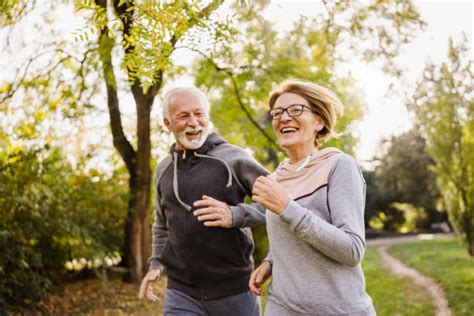 Pareja de ancianos corriendo en el parque, simbolizando actividad física en la tercera edad.