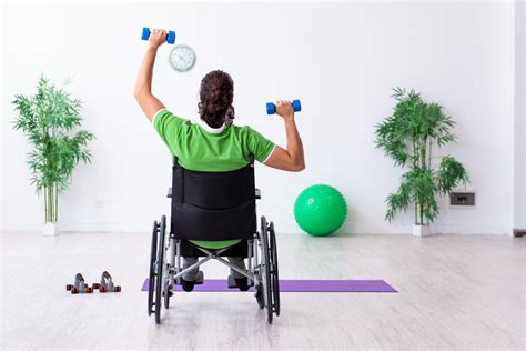 Persona con discapacidad en silla de ruedas realizando ejercicios de levantamiento de pesas en un gimnasio adaptado.