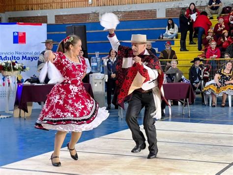 Pareja de adultos mayores bailando cueca con pañuelos