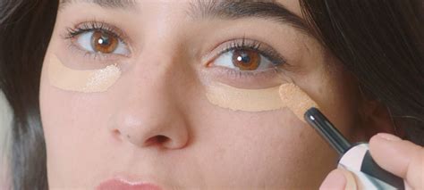 Fotografía de una mujer aplicando primer en sus párpados o corrector en el área de los ojos