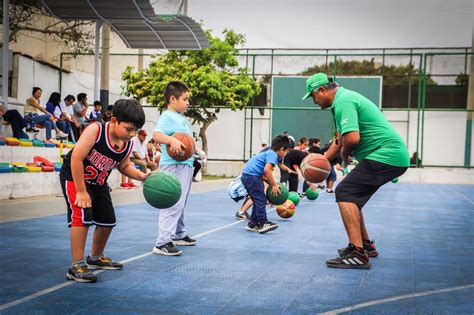 Niños y adolescentes participando activamente en talleres deportivos al aire libre en un parque