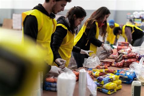 Foto de voluntarios de un banco entregando canastas de alimentos a familias
