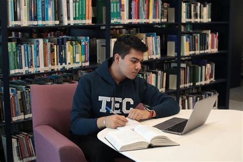 Estudiante joven estudiando en una biblioteca con libros.