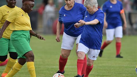 Foto de abuelas jugando al fútbol con uniformes coloridos en Sudáfrica durante un torneo internacional.