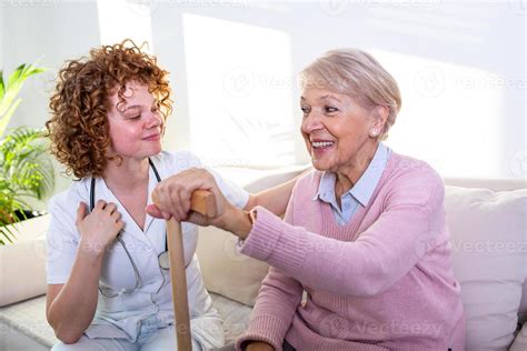 Foto de una cuidadora interactuando amablemente con un adulto mayor en casa