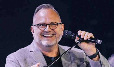 Marcos Witt cantando en un concierto, con gente levantando las manos