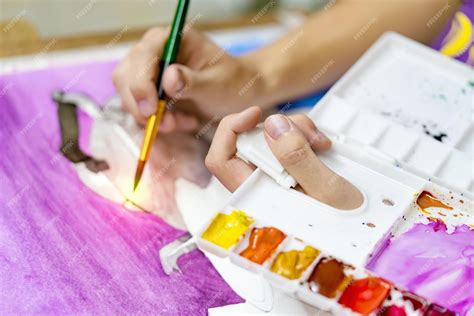 Primer plano de manos de persona mayor sosteniendo un pincel y pintando