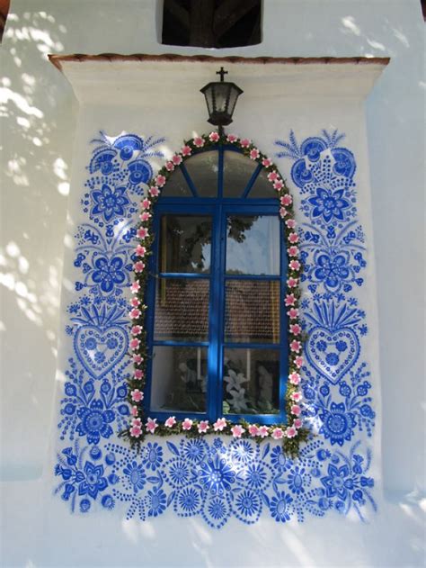 Mujer de 90 años, Agnes Kasparkova, pintando intrincados diseños florales en azul ultramarino sobre una fachada blanca de una casa rural