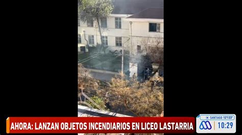 Estudiantes encapuchados lanzando objetos incendiarios en un liceo